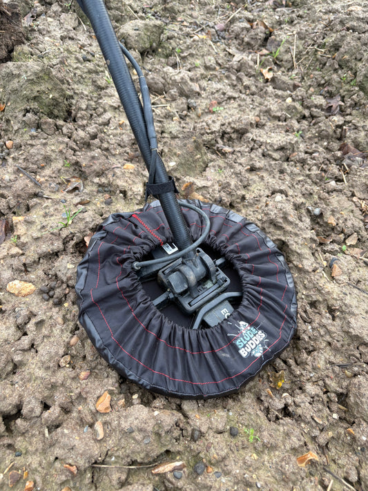 Sludge Buddies 11-inch coil cover fitted on a metal detector during field testing in muddy conditions.
