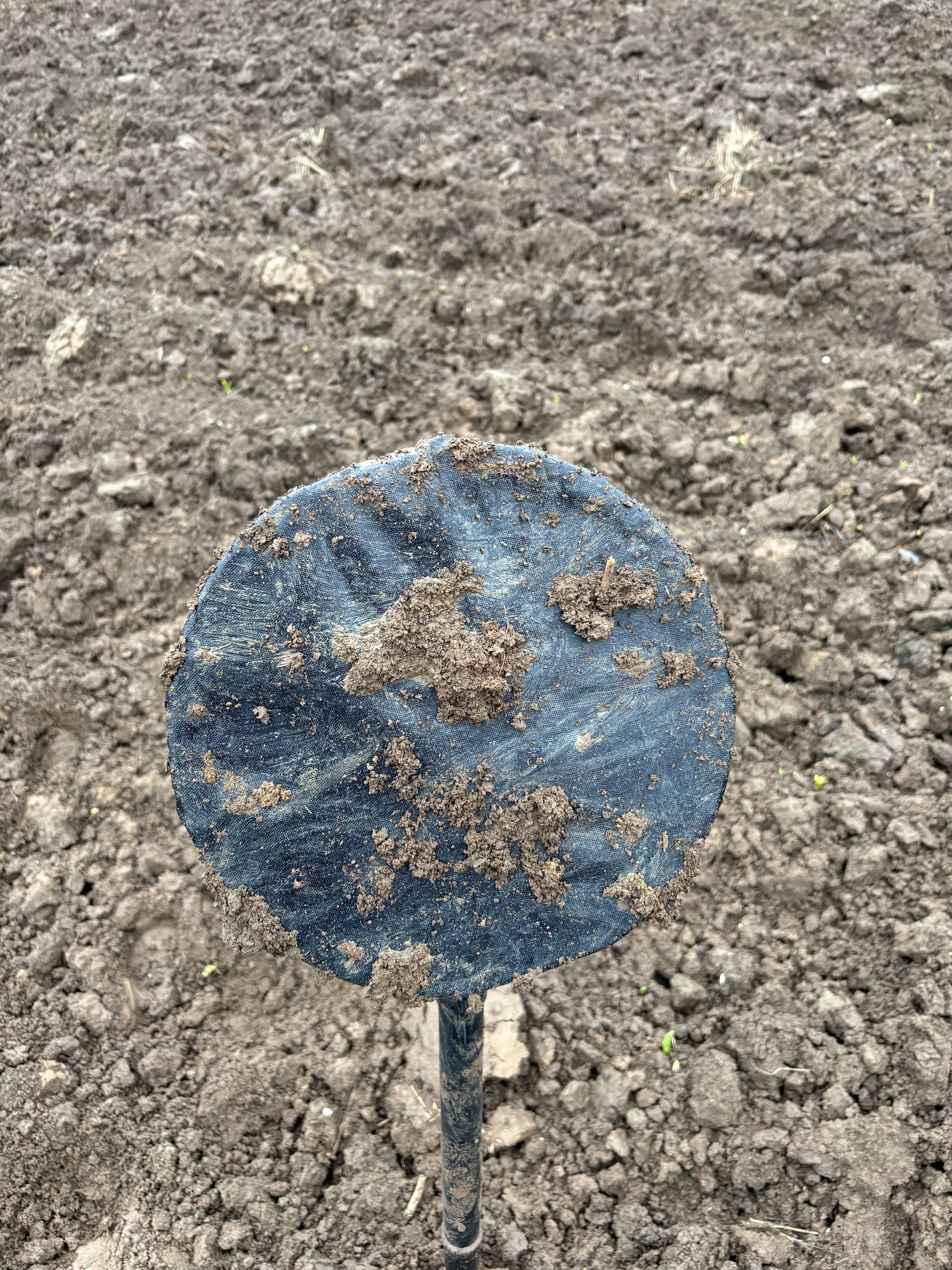 Underside of a Sludge Buddies coil cover during a muddy field test.