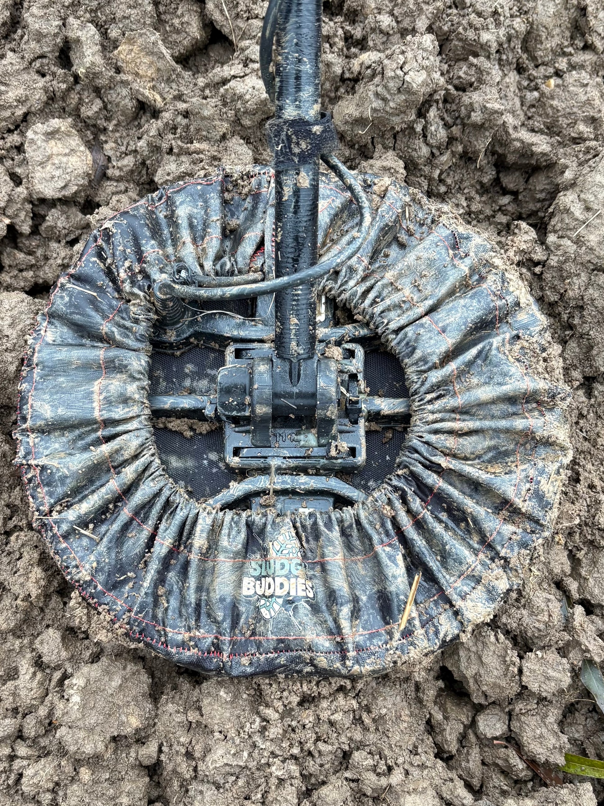 Sludge Buddies coil cover in heavy mud during a real-world field test.
